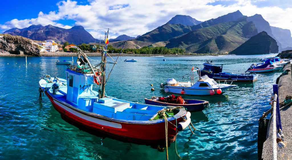 Barche da pesca ancorate nel porto di Agaete, Tenerife, con montagne sullo sfondo.