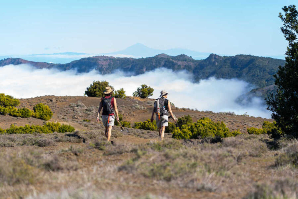 Escursionisti camminano su un sentiero montuoso a Tenerife con vista nuvolosa.