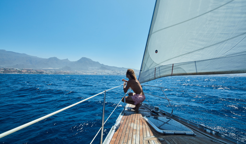 Uomo su una barca a vela al largo della costa di Tenerife.