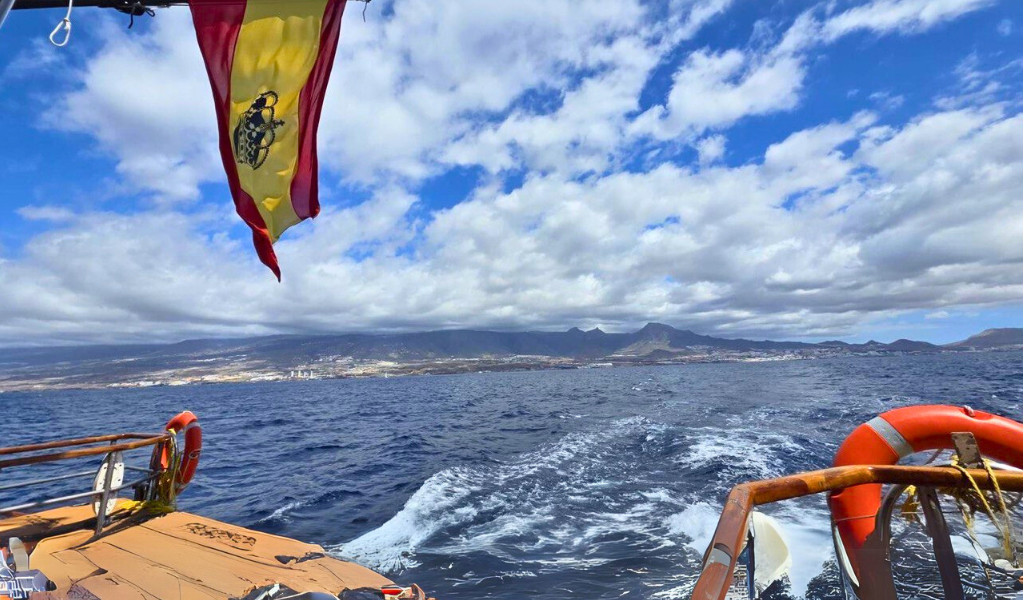 Barca in mare con bandiera spagnola, vista di Tenerife all'orizzonte.