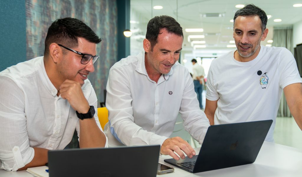 Tre uomini discutono lavorando al computer in ufficio a Santa Cruz de Tenerife.