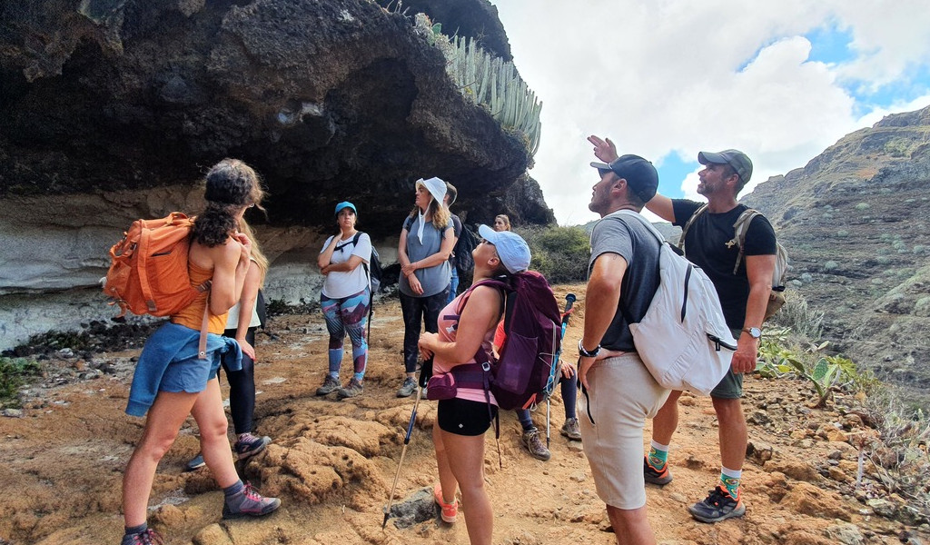 Escursionisti sotto una roccia con cactus a Tenerife.