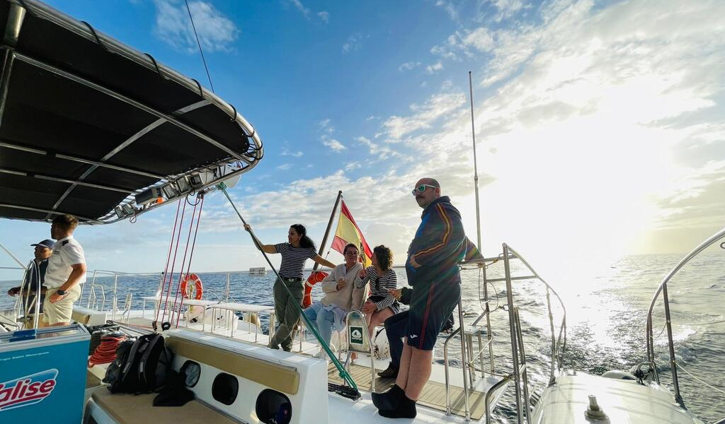 Persone su una barca a vela nel mare di Tenerife al tramonto.