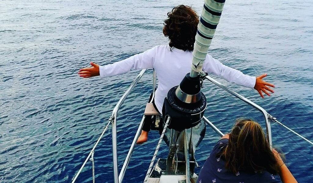 Bambini seduti a prua di una barca in mare aperto vicino a Tenerife.