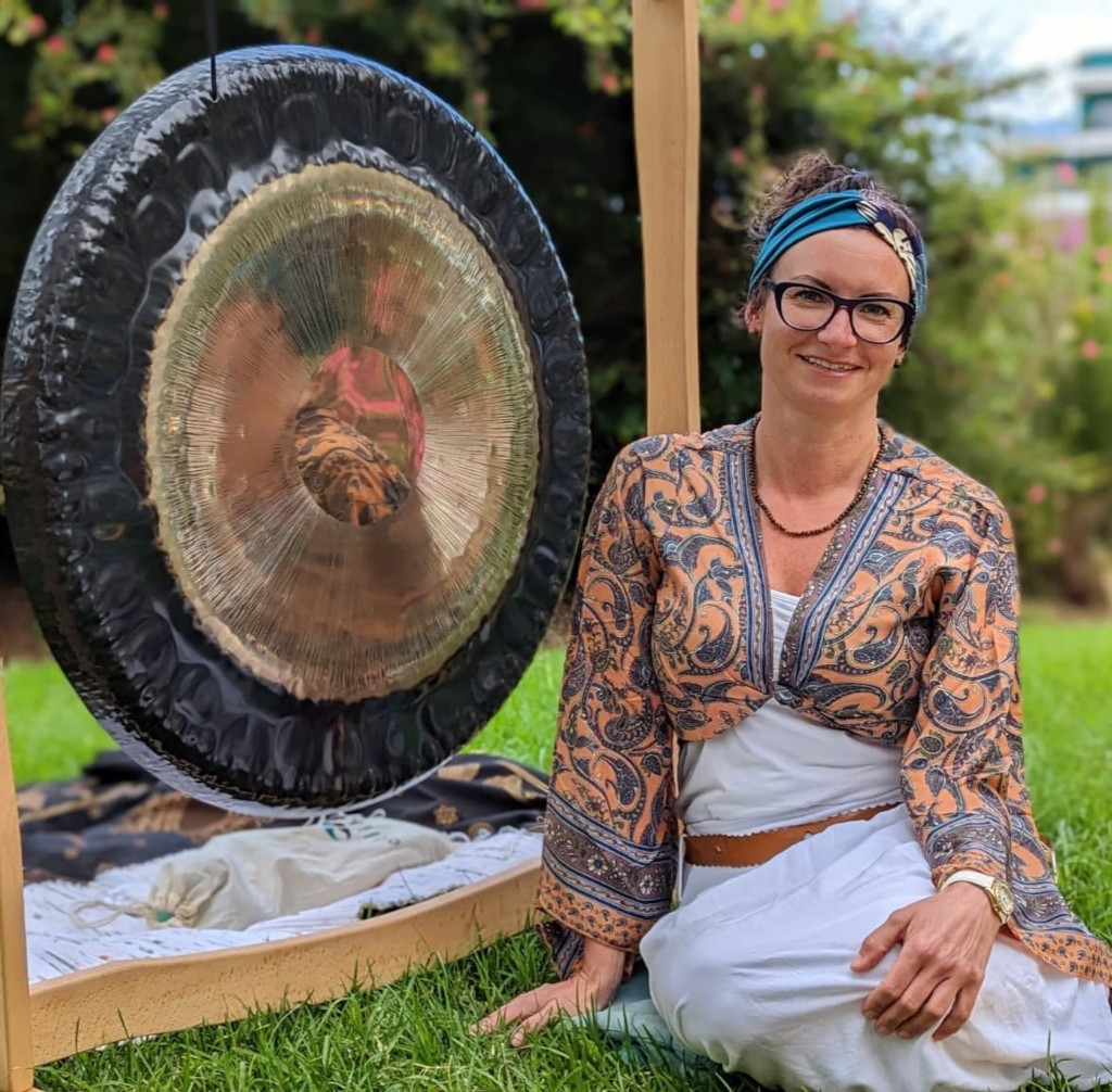 Donna seduta accanto a un grande gong in giardino a Tenerife.
