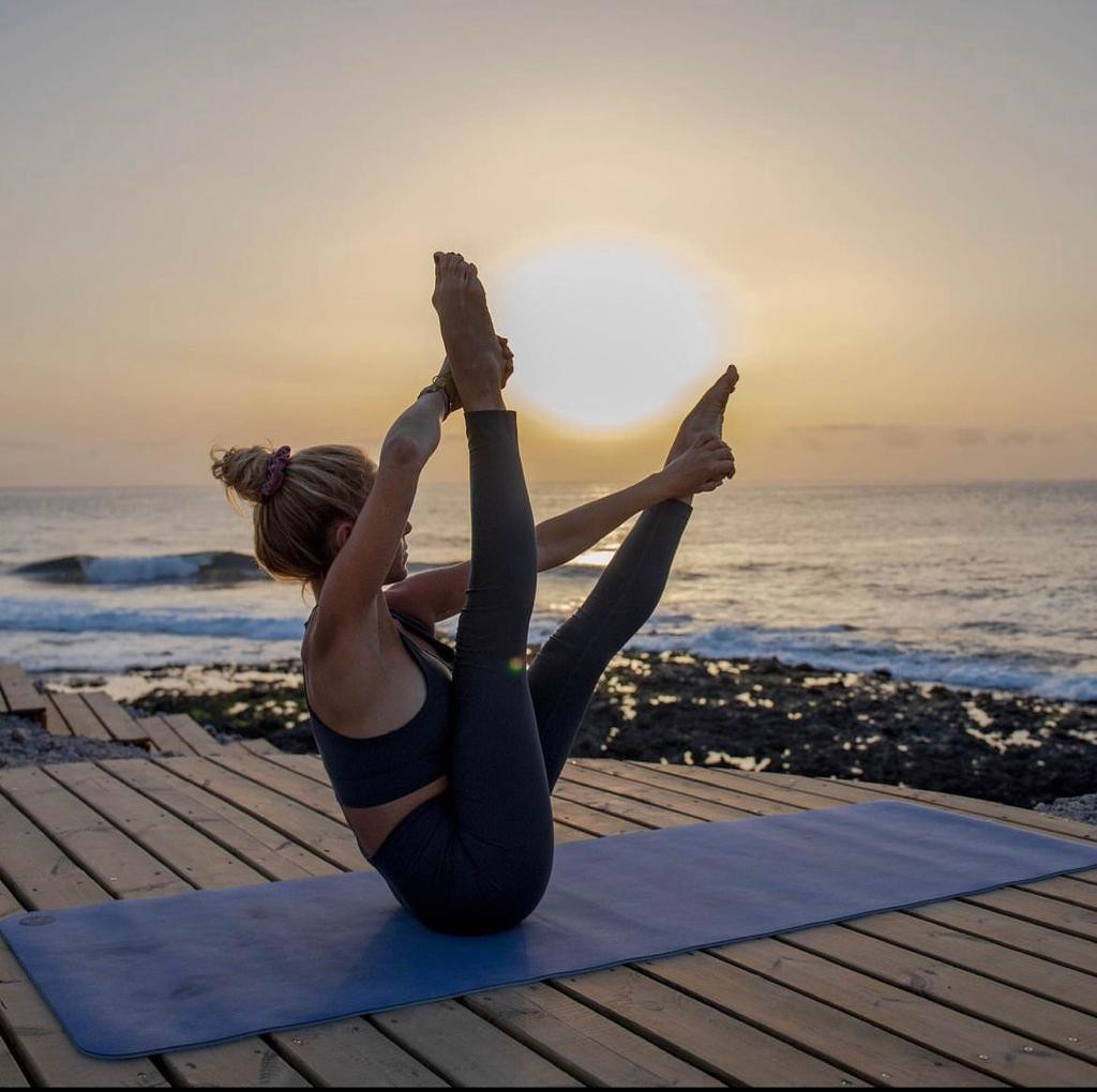 Donna fa yoga al tramonto su una terrazza vicino al mare a Tenerife.