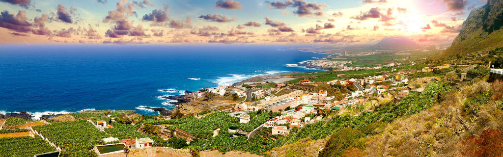 Vista panoramica di un villaggio costiero a Tenerife con oceano e montagne.