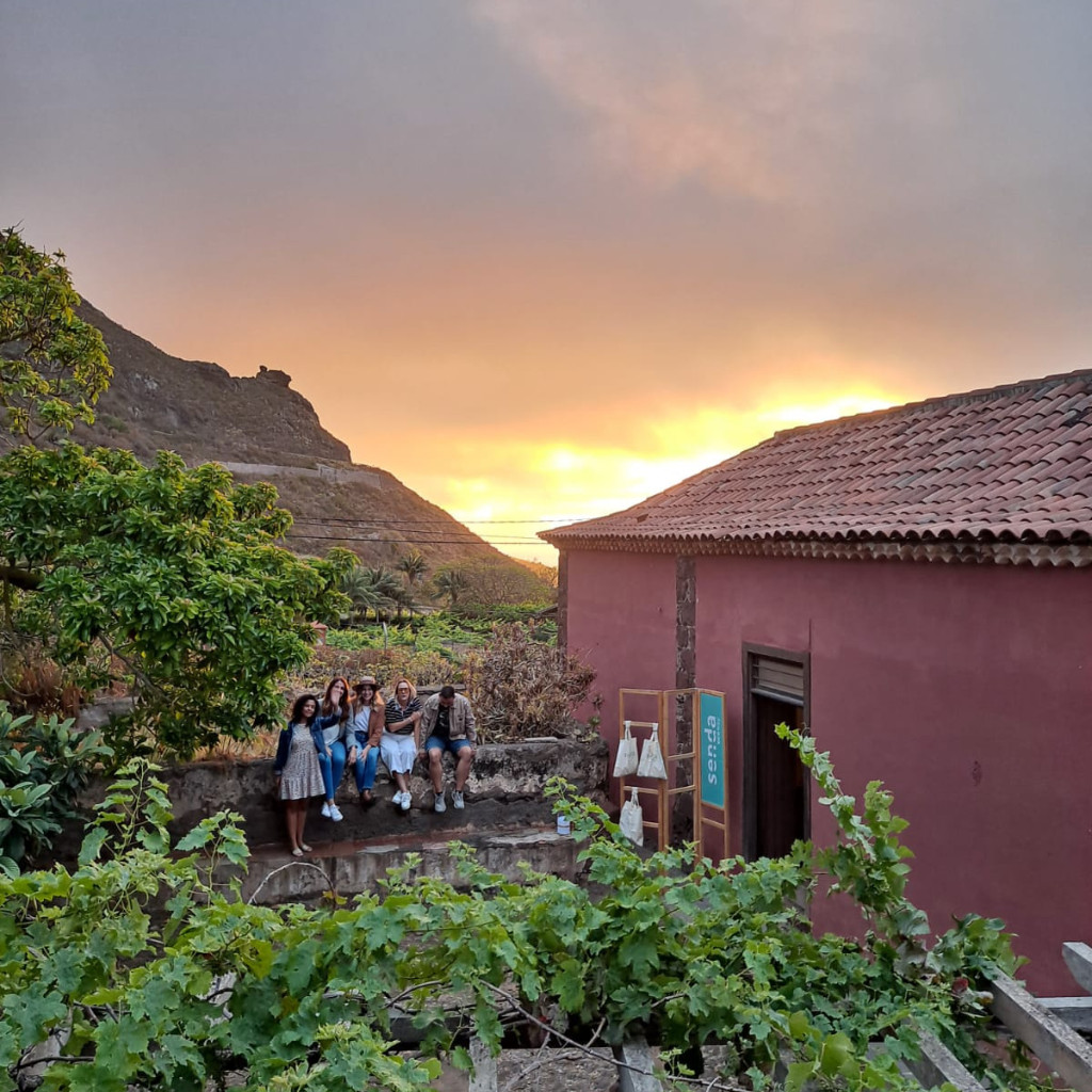Gruppo di persone sedute su un muretto al tramonto a Buenavista, Tenerife.