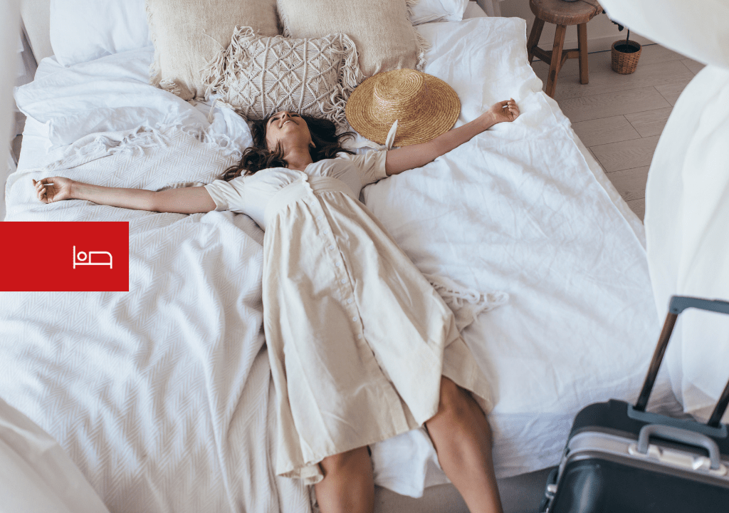 Persona che riposa su un letto accanto a una valigia e un cappello a Tenerife.