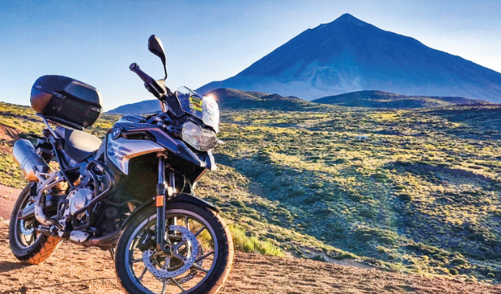 Moto parcheggiata davanti al Monte Teide a Tenerife sotto cieli azzurri.