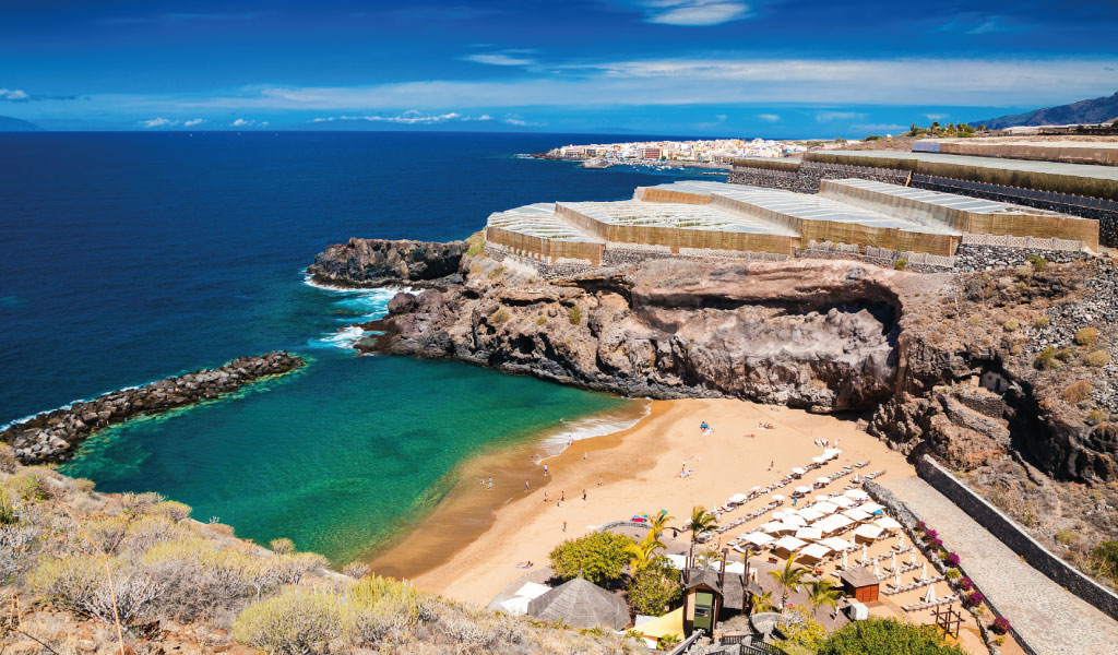 Spiaggia con ombrelloni e mare azzurro a Puerto de Santiago, Tenerife.
