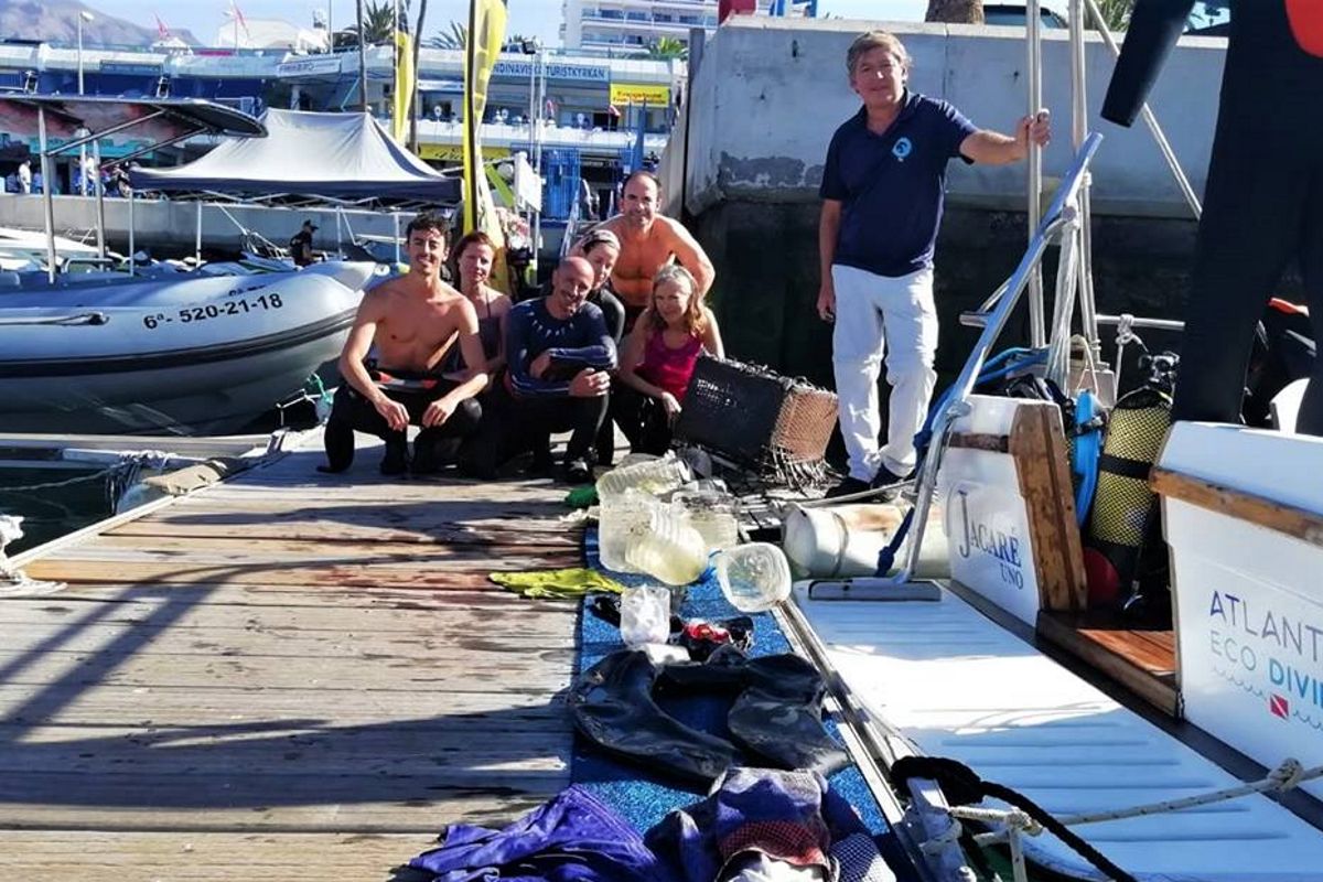 Persone sul molo con attrezzature da immersione e raccolta rifiuti a Tenerife.