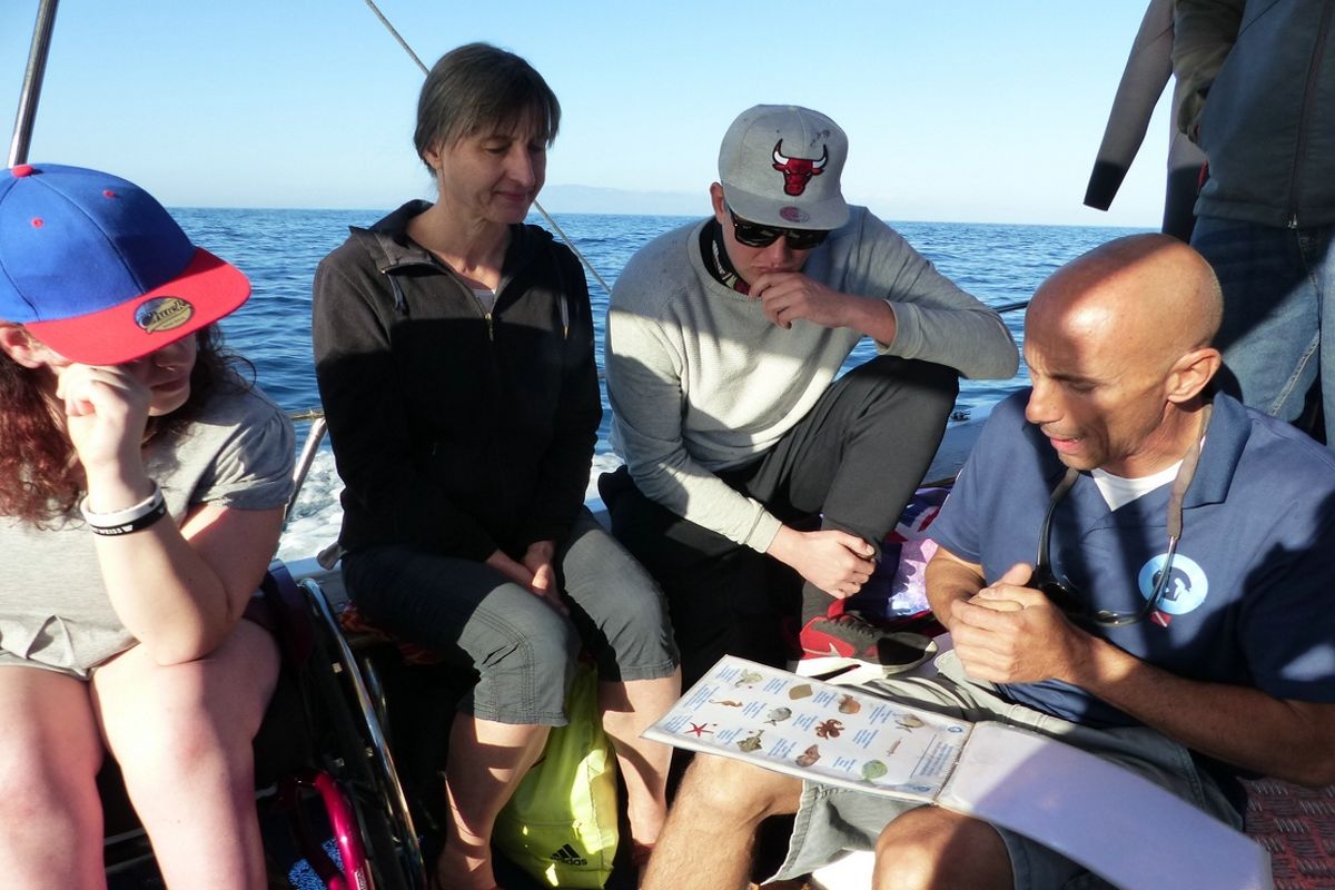 Le persone su una barca a Tenerife guardano una lista con immagini e testi mentre navigano.