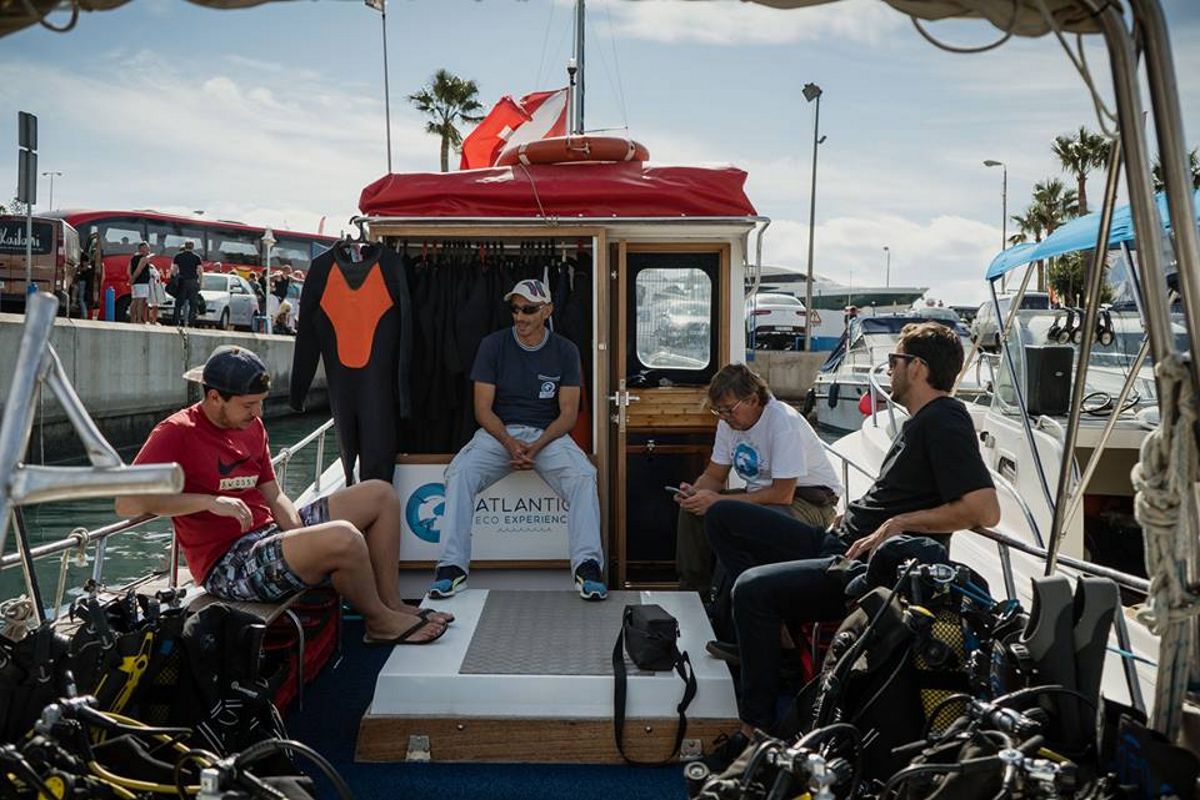 Persone sedute su una barca da immersione a Puerto Colón, Tenerife, in mute da neopreno.
