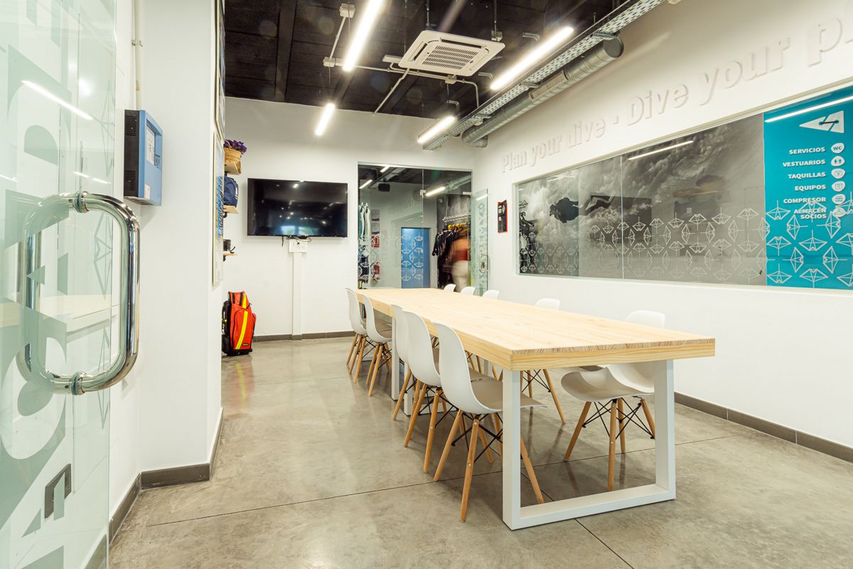 Sala riunioni con lungo tavolo e sedie bianche nel centro immersione di Tenerife.