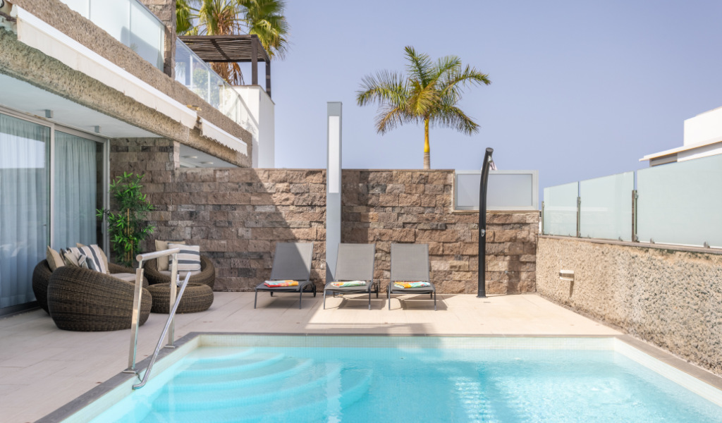 Piscina all'aperto con sedie e palma in un hotel a Tenerife.