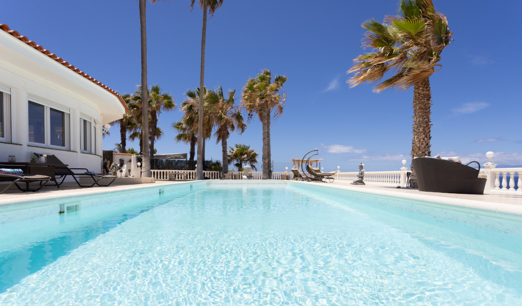 Piscina all'aperto con palme a Tenerife sotto un cielo limpido.