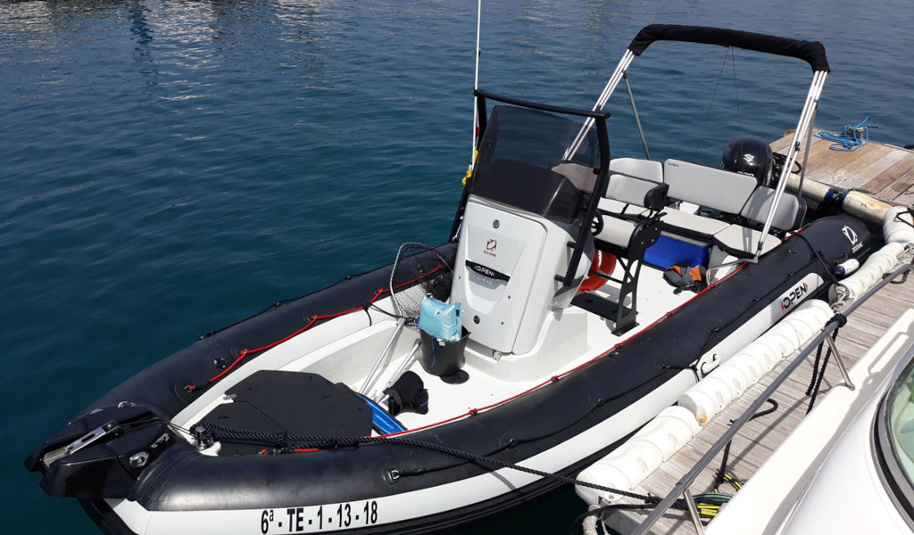 Gonfiabile ormeggiata nel porto di Tenerife, con sedili e motore visibili.