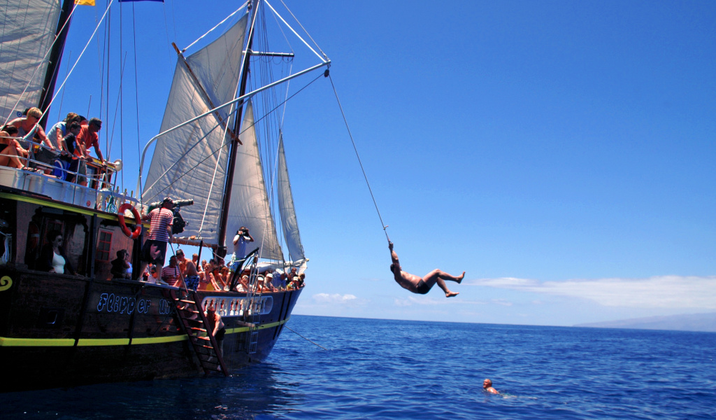 La persona salta da una barca turistica al mare sulla costa di Tenerife.