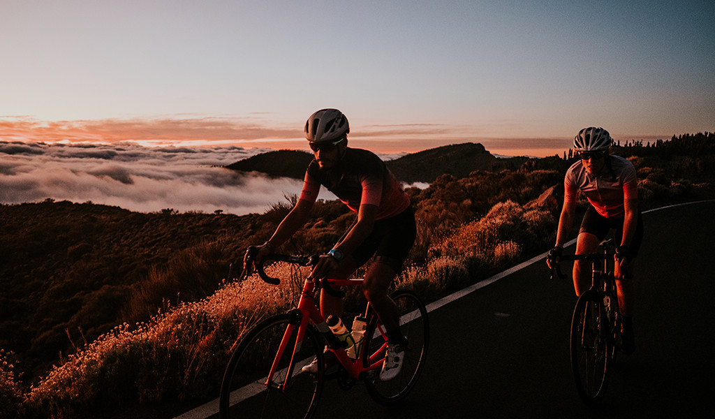 Ciclisti su strada con paesaggi montuosi al tramonto a Tenerife.