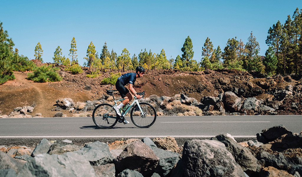 Ciclista su strada circondata da alberi e rocce a Tenerife.