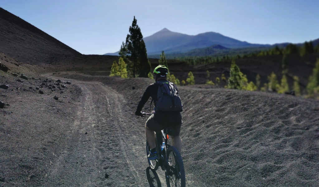Ciclista su un sentiero vulcanico con il Monte Teide sullo sfondo a Tenerife.