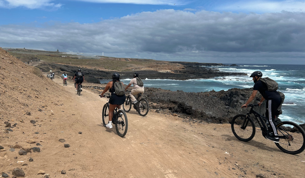 Ciclisti che percorrono un sentiero costiero a Tenerife, lungo il mare e il cielo nuvoloso.