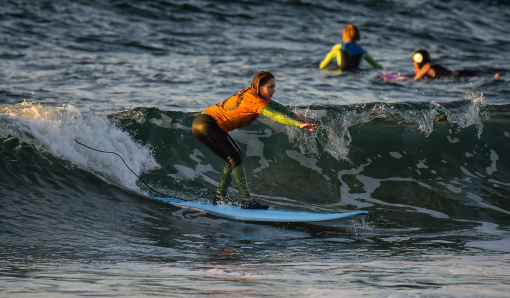 Surfista sulla spiaggia di Tenerife che cavalca un'onda al tramonto.