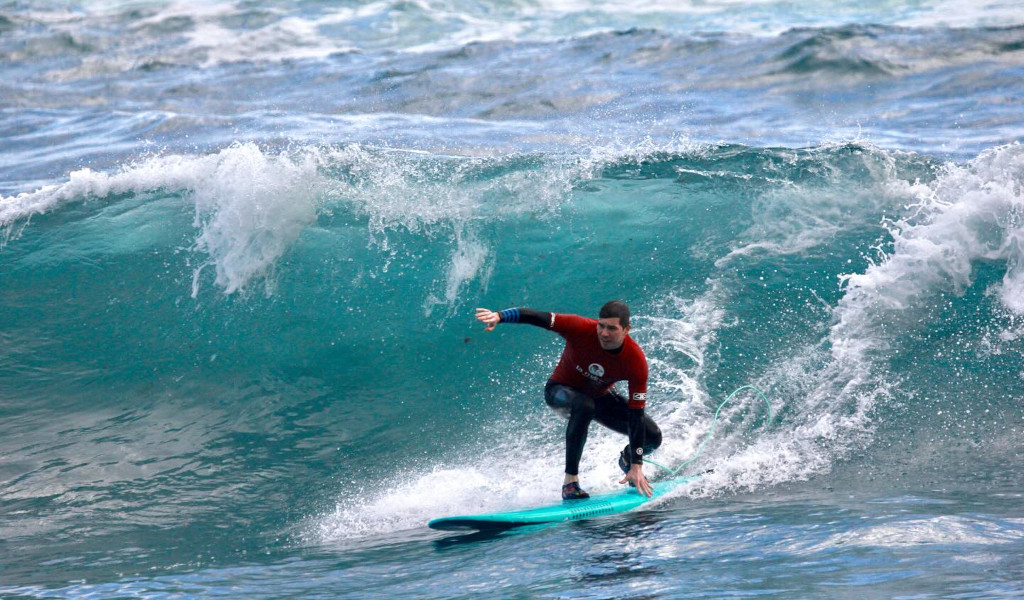 Surfista che cavalca un'onda sulla spiaggia di Tenerife.