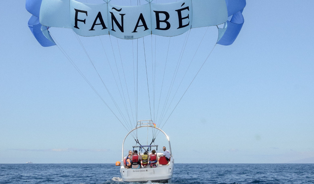 Persone che fanno parasailing a Fañabé, Tenerife, sopra mare.