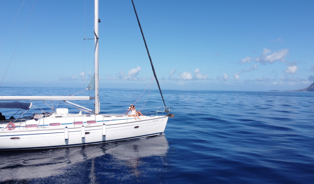 Barca a vela che naviga nelle acque di Tenerife sotto un cielo limpido.