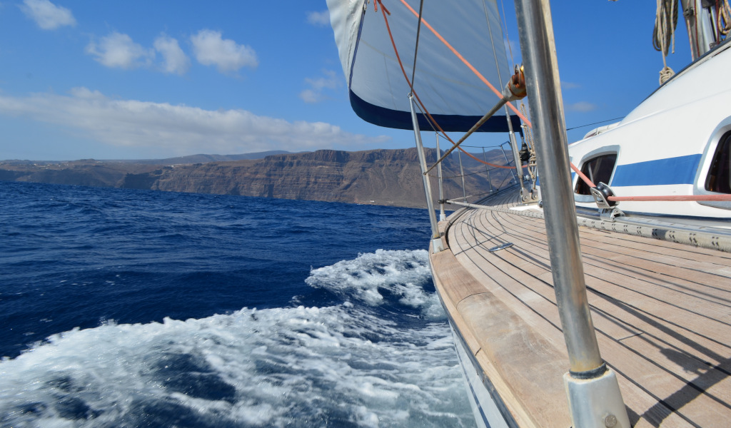 Barca a vela vicino alla costa di Tenerife con montagne sullo sfondo.