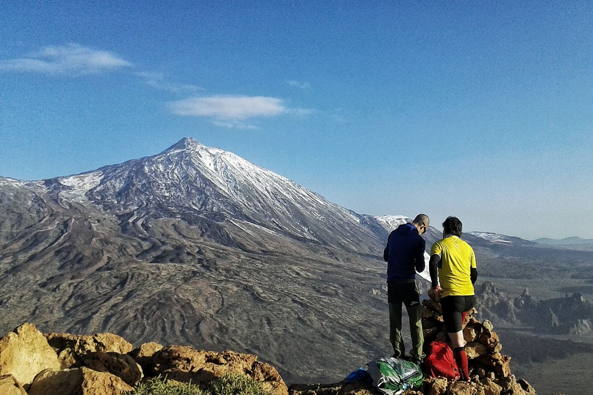 Due persone in piedi a un punto panoramico che domina il vulcano Teide a Tenerife.