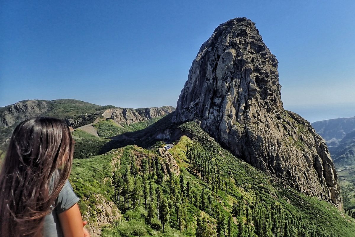 Donna che osserva il Roque de Agando a Tenerife, circondata dalla vegetazione.