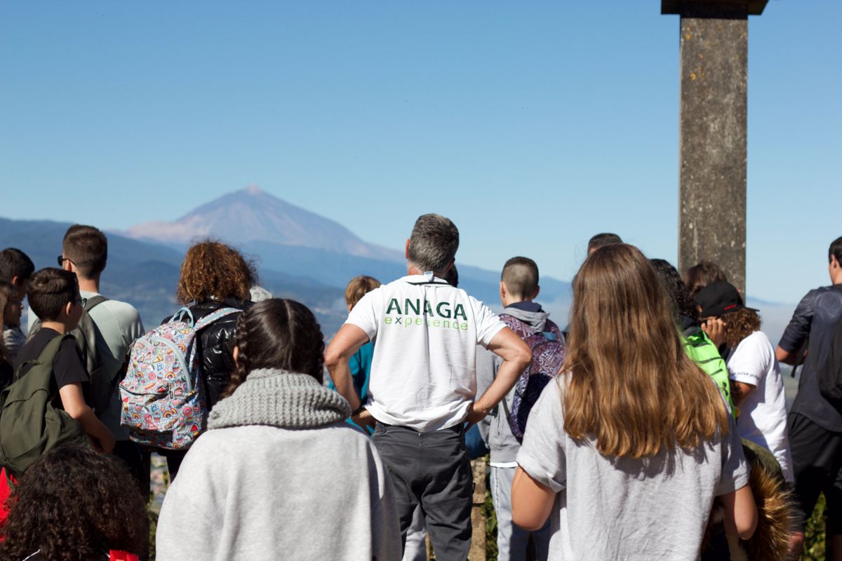 Il gruppo osserva il paesaggio con il Monte Teide sullo sfondo, la guida indossa la maglietta ANAGA experience.