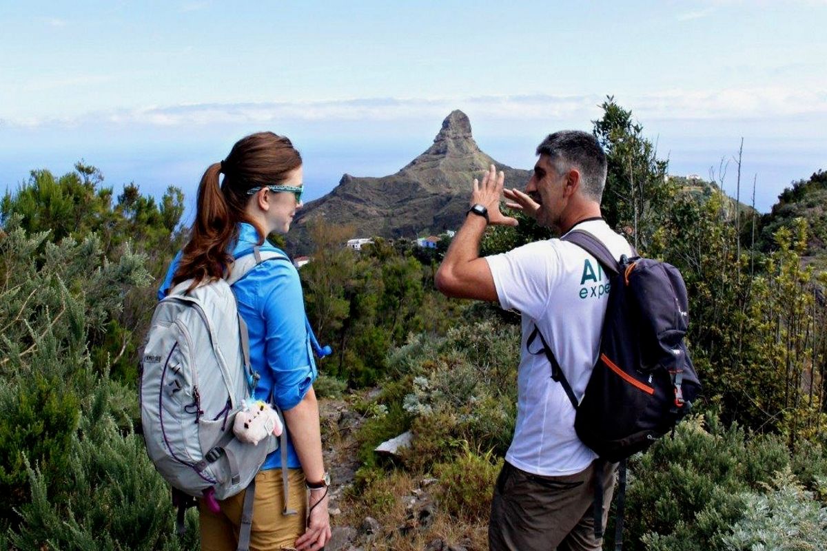 Due persone parlano su un sentiero di montagna a Tenerife, con montagne sullo sfondo.