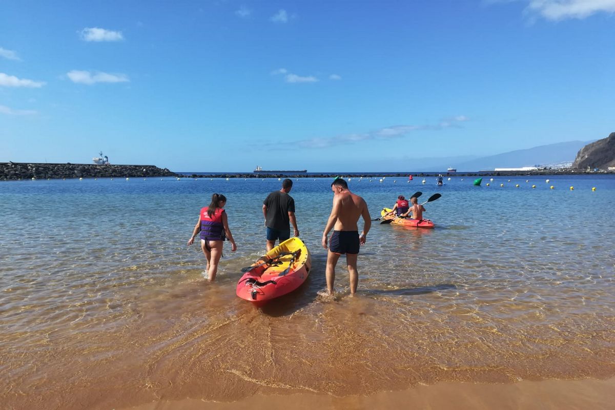 Le persone portano kayak in mare a lungo la spiaggia di Las Teresitas, Tenerife.