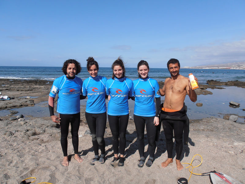 Gruppo di surfisti sulla spiaggia di Tenerife in mute blu.