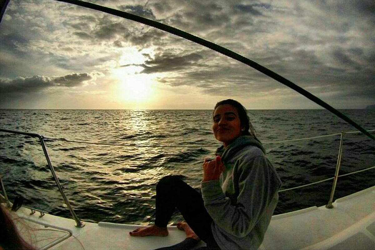 Persona seduta su una barca al tramonto vicino alla costa di Tenerife.