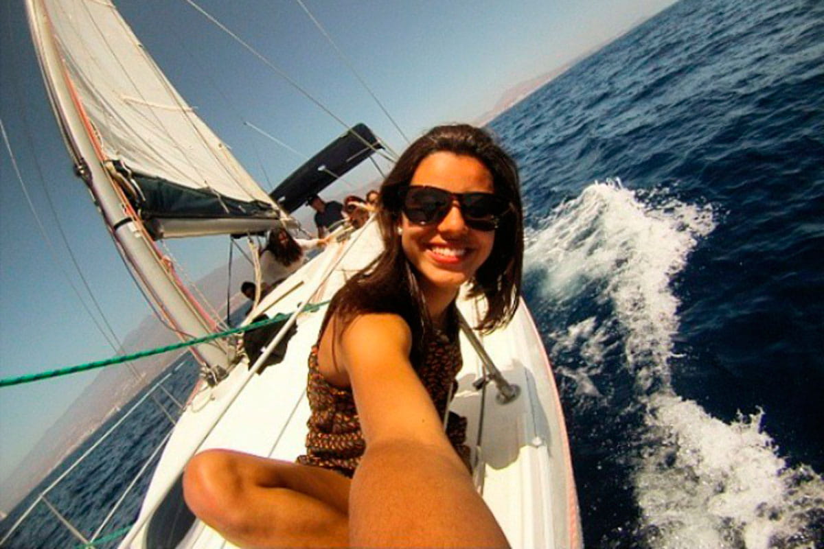 Persona che sorride su una barca a vela che naviga vicino alla costa di Tenerife.