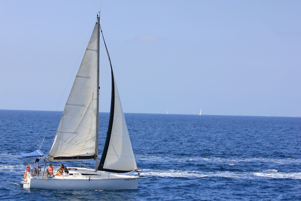 Barca a vela che naviga attraverso le acque di Tenerife con cieli limpidi.