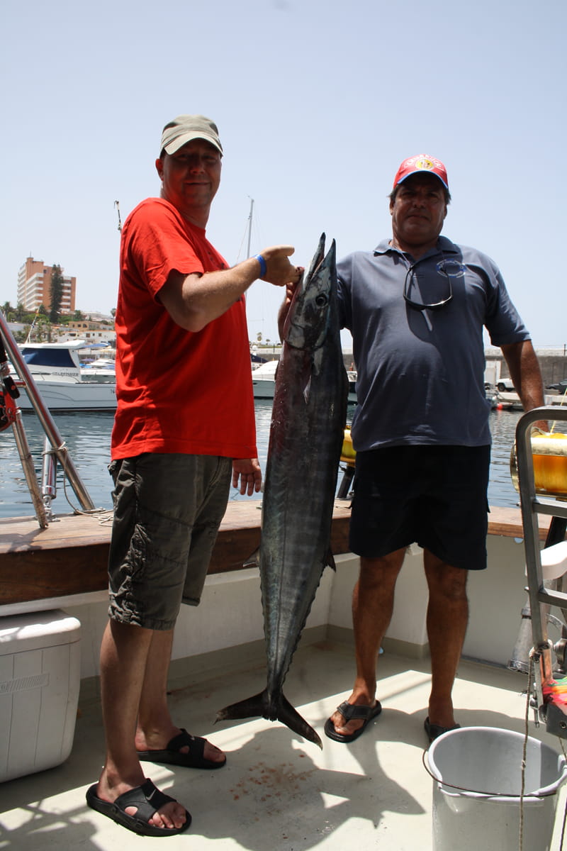 Due persone su una barca che tengono un grosso pesce a Los Cristianos, Tenerife.