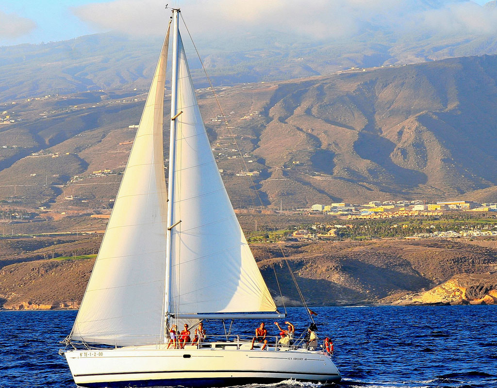 Barca a vela vicino alla costa di Tenerife con montagne sullo sfondo.