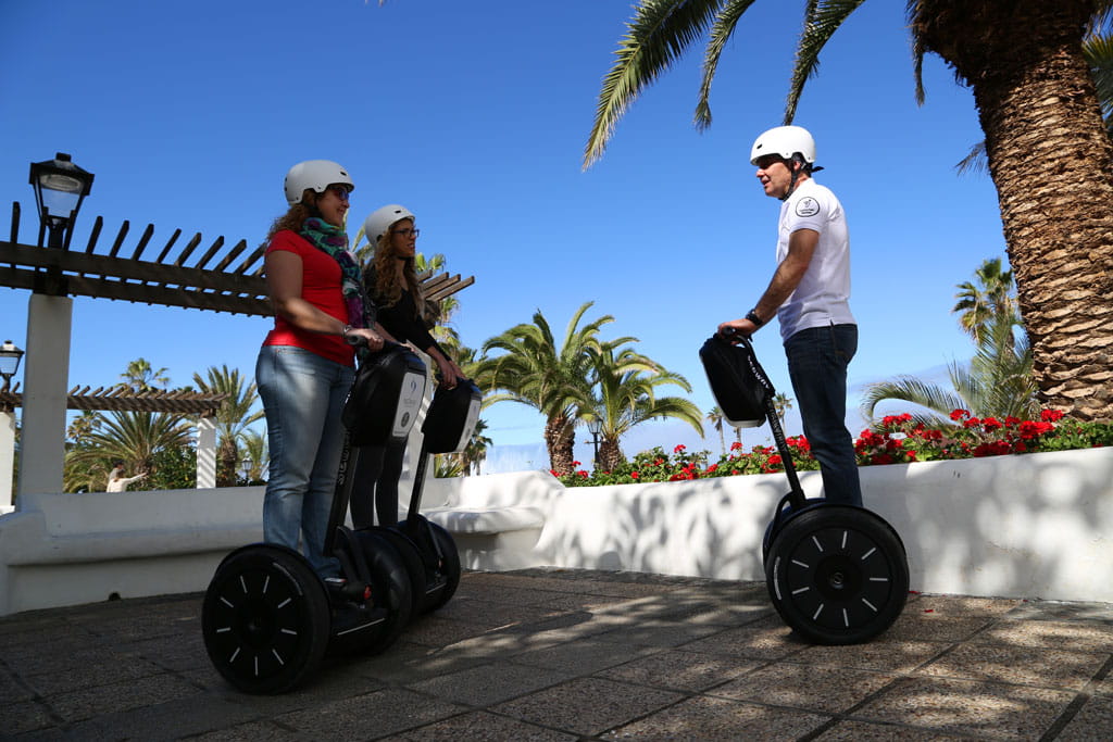 Persone su segway che camminano tra le palme a Tenerife.