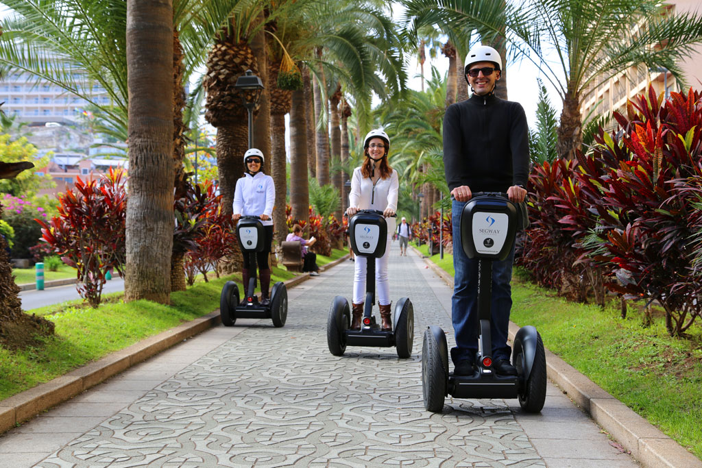 Tre persone su segway percorrono un viale fiancheggiato da palme a Tenerife.