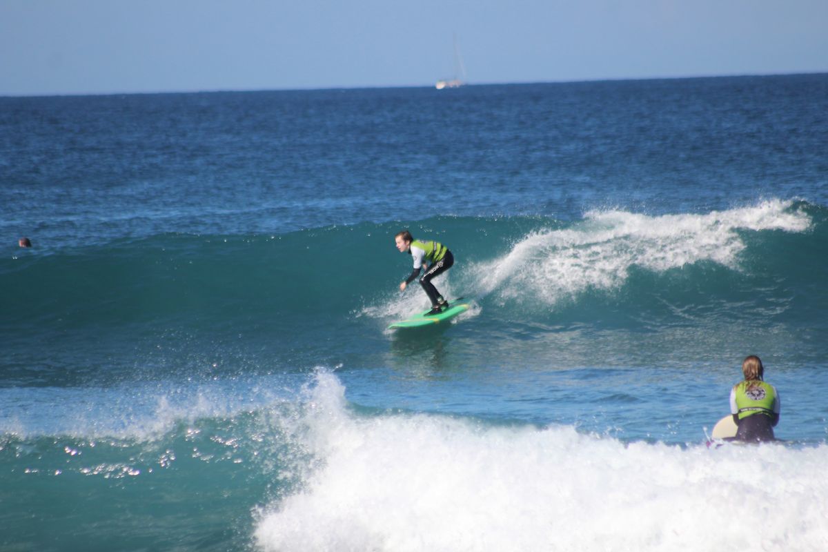 Surfista cavalcando un'onda a Tenerife, con un'altra persona che osserva dall'acqua.