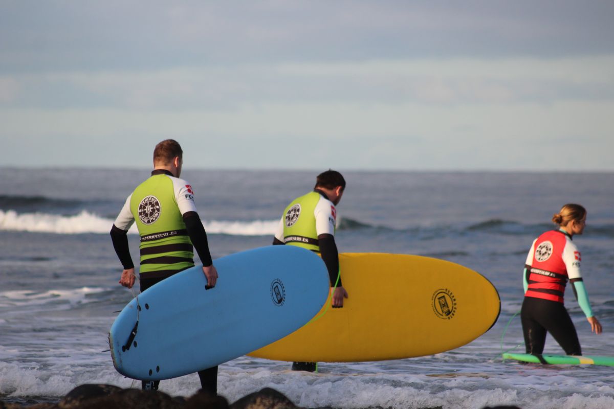 Surfisti che entrano in mare con tavole colorate a Tenerife.