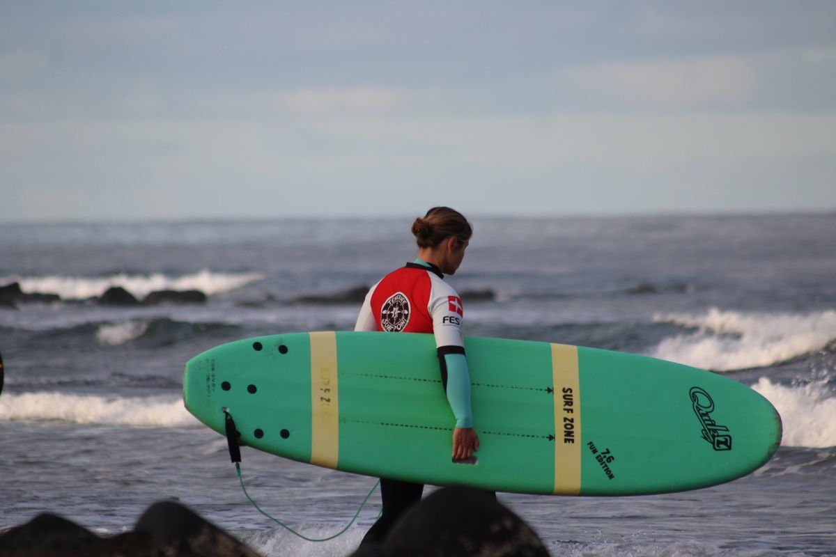 persona con la tavola da surf verde sulla spiaggia a Tenerife