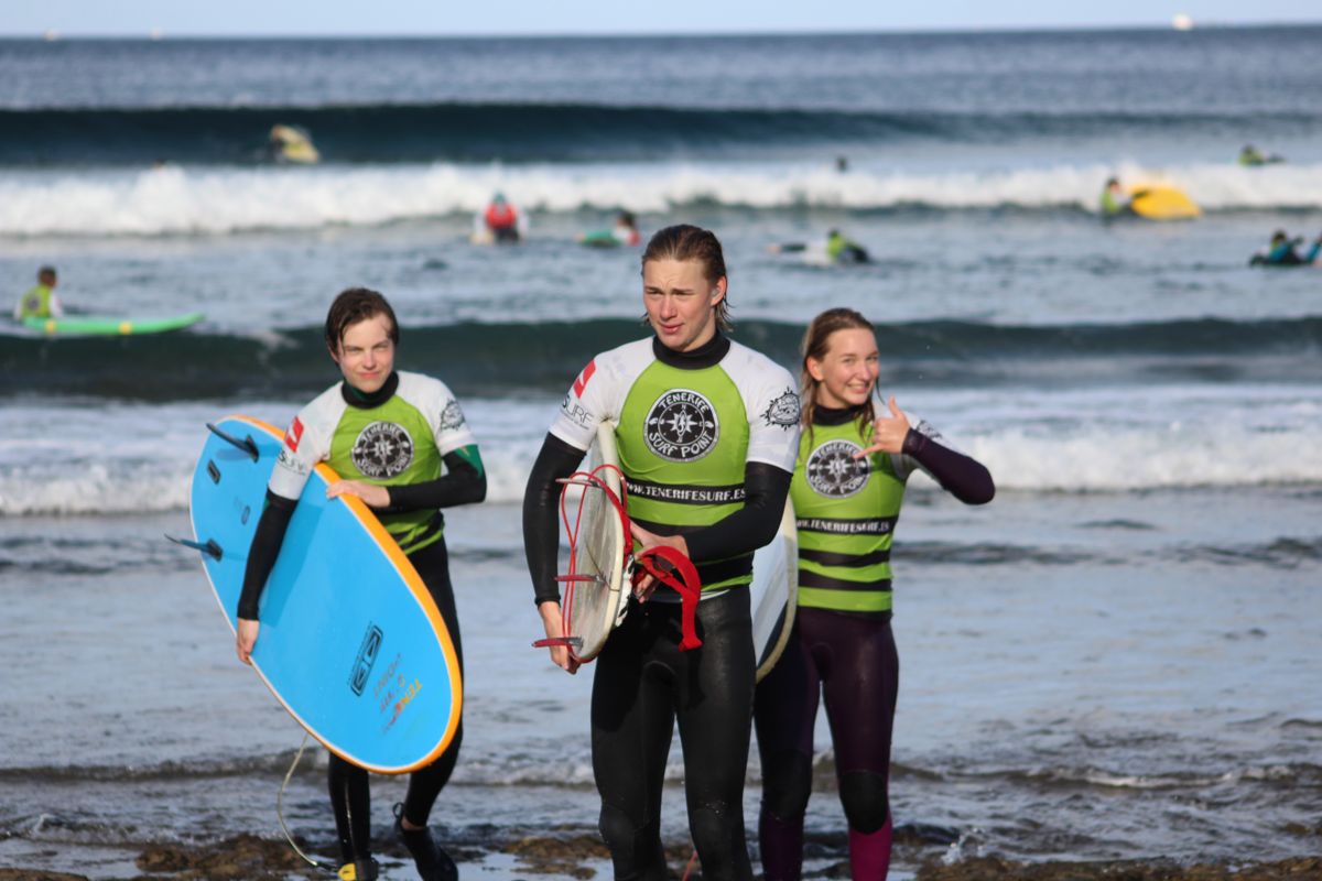 Surfisti sulla spiaggia di Tenerife, con tavole e mute, vicino al mare.