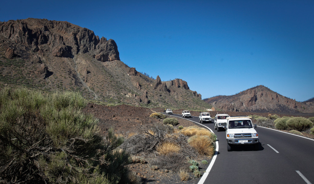 Carovana di auto sulla strada per il Monte Teide, Tenerife, circondata da montagne.